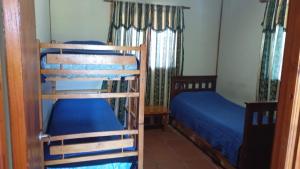 two bunk beds in a room with blue sheets at CABAÑA AKAPANA in Huerta Grande