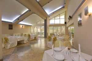 a restaurant with white tables and chairs and windows at Hotel Alexandros Busteni by Genco & Restaurant Miorita in Buşteni