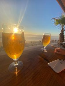 two glasses of beer sitting on a table on the beach at VILLA LACANAU OCÉAN DANS LE GOLF in Lacanau-Océan