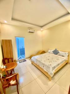 a bedroom with a bed and a table and a window at Nhà nghỉ Kim Cương in Rach Gia
