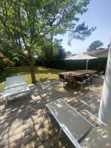 a patio with a table and chairs and an umbrella at VILLA LACANAU OCÉAN DANS LE GOLF in Lacanau-Océan +55 photos