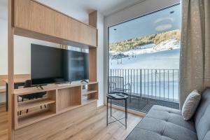 a living room with a television and a balcony at Apart Sonnenbichl in Sölden