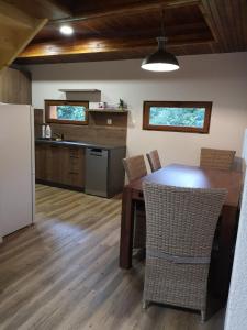 a kitchen with a wooden table with chairs and a refrigerator at Cabin near forest in Mlynčeky