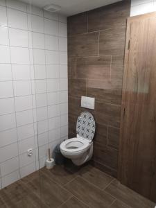 a bathroom with a toilet with a wooden wall at Cabin near forest in Mlynčeky