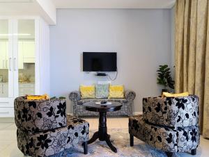 a living room with two chairs and a table and a tv at Golden Oasis at Itowers in Gaborone