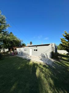 a white house with a garage and a grass yard at Casa estilo campestre a pasos del mar in Santa Clara del Mar