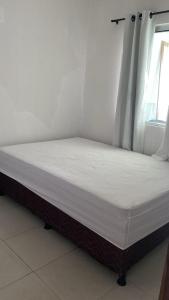 a bed in a room with a white mattress at Chalé Di vino in Porto Seguro