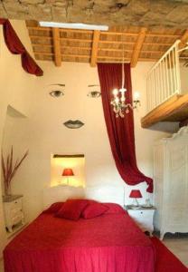 Un dormitorio con una cama roja con una cara en la pared en Bed & Breakfast Barbara, en Borgo Grotta Gigante