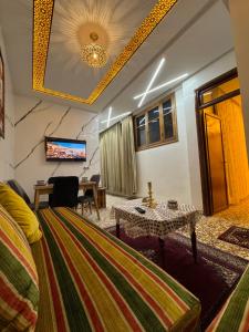 a room with a bed and a table and a television at Appartement Dar LALA 2 in Fez