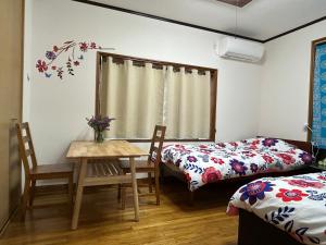 a room with two beds and a table and chairs at 民泊みどりやね in Ibusuki