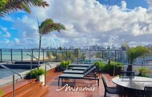 a deck with tables and chairs and a view of the city at Alta Garden- Pé Na Areia- MH in João Pessoa