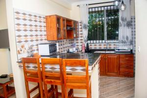 a kitchen with wooden cabinets and a counter with two chairs at VvEK B&B APARTMENT in Arusha