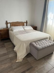 a bedroom with a large bed with a ottoman and a window at hospedaje la familia in Villa Lía