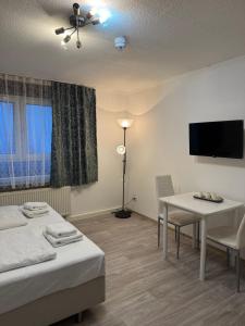 a room with two beds and a table and a tv at Hotel-Pension Alt-Heidenberg in Siegen