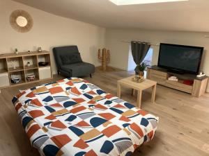 a bedroom with a bed and a tv and a chair at Joli petit appartement in Eymet