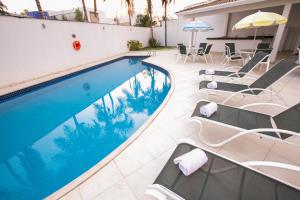 a swimming pool with chairs and an umbrella at Verona Hplus Long Stay in Brasília