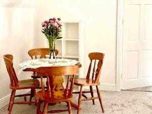 stół i krzesła z wazonem kwiatów na nim w obiekcie Fionas thatched cottage eile w Killarney
