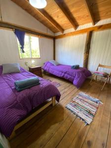 two beds in a room with wooden floors at Lugar bonito casa de dos habitaciones in El Bolsón