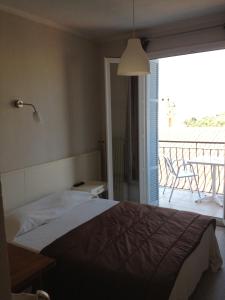 a bedroom with a bed and a view of a balcony at Hotel Cyrnos in Cargèse