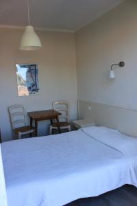 1 dormitorio con 1 cama blanca, mesa y sillas en Hotel Cyrnos, en Cargèse