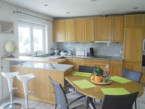a kitchen with wooden cabinets and a table and chairs at Appartement entier LEA avec petit déjeuner in Hilsprich