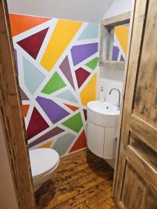 a bathroom with a toilet and a colorful wall at Chez Tantine in Troyes