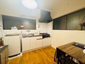 una cucina con mobili bianchi, un lavandino e un tavolo di Oji House-KI0022 a Tokyo