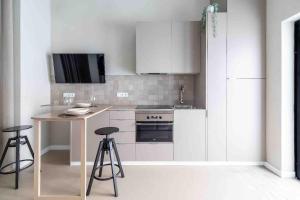 a kitchen with white cabinets and a table and stools at Valencia Malvarrosa point beige in Valencia