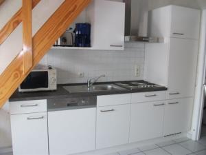 a white kitchen with a sink and a microwave at Gemütliches und ruhiges Ferienhaus im Seebad Bredene aan Zee in Bredene