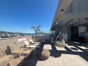 a balcony with chairs and tables and a building at Apto com piscina aquecida perto do mar in Bombinhas