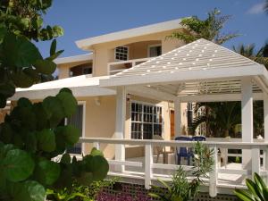 a white pergola in front of a house at Paradise Beach Hotel in West Bay