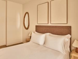 a bedroom with a bed with white pillows and a mirror at Apartamentos Turísticos Casa de La Borrega in Estepona