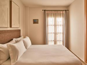 a bedroom with a white bed with a window at Apartamentos Turísticos Casa de La Borrega in Estepona