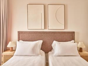 two beds in a bedroom with two pictures on the wall at Apartamentos Turísticos Casa de La Borrega in Estepona