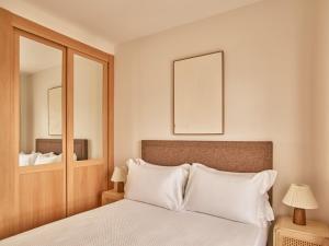 a bedroom with a bed with white pillows and a mirror at Apartamentos Turísticos Casa de La Borrega in Estepona