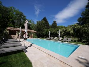 a swimming pool with chairs and umbrellas next to it at Mas Château Blanc in Avignon