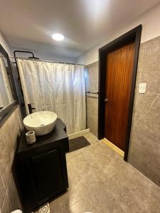 a bathroom with a sink and a wooden door at Villa Victoria in Manantiales +11 photos