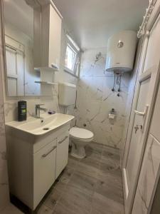 a white bathroom with a toilet and a sink at Apartman Rim 