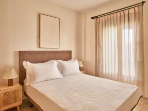a bedroom with a bed with white sheets and a window at Apartamentos Turísticos Casa de La Borrega in Estepona