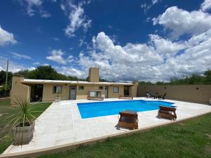 a swimming pool with two chairs and a house at Cabañas Emilia in Mina Clavero