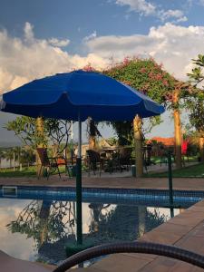 Una sombrilla azul junto a una piscina. en Rancho Green22Home, en Ibiraci