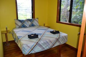 a bedroom with a bed with two black shoes on it at Licensed 2 bedroom cabin Close to San Ignacio, local dining, and adventure tours in San Ignacio
