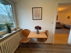 a table with two chairs and a vase with flowers on it at Apartment am Messegelände in Nürnberg