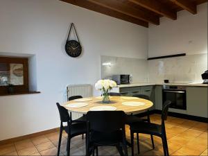 a kitchen with a table with chairs and a clock on the wall at Le mas du Pilat in Bessey