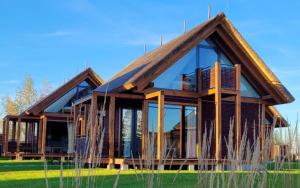 a large house with glass windows on a field at Domki Kuter Port in Gdów