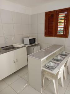 a kitchen with a counter and a table with plates on it at Casa da Lalá in Fortaleza