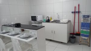 a white kitchen with a counter and a microwave at Casa da Lalá in Fortaleza +11 photos