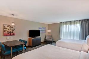 a hotel room with two beds and a desk and a tv at TownePlace Suites by Marriott Panama City Beach Pier Park in Panama City Beach