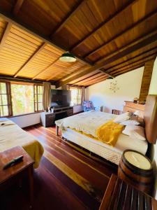 - une grande chambre avec 2 lits et un plafond en bois dans l'établissement Casa da Mel, à Itatiaia