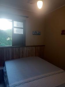 a bedroom with a large bed with a window at Casa Centro pertinho da praia in Piúma